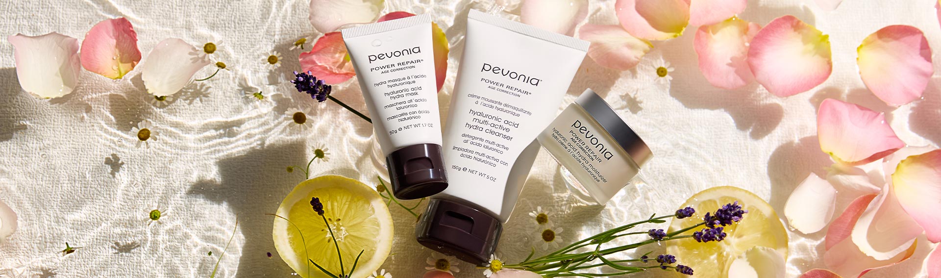 Pevonia Hyaluronic Acid Line floating in shallow water with pink petals.