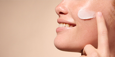 A woman applying Pevonia Marine Collagen Cream onto her cheek.