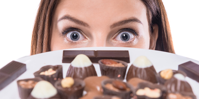 A woman peering over a plate full of Chocolates.