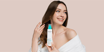 A woman holding Pevonia's Hyaluronic Acid HydraMist.