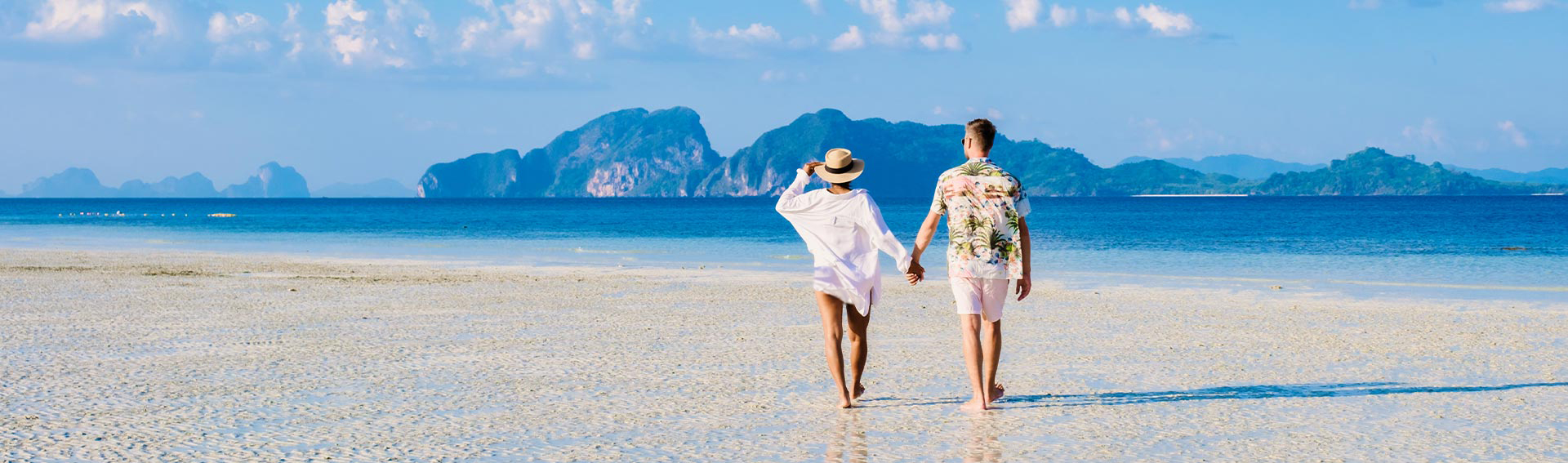 A couple walking by the ocean on a bright summer day.